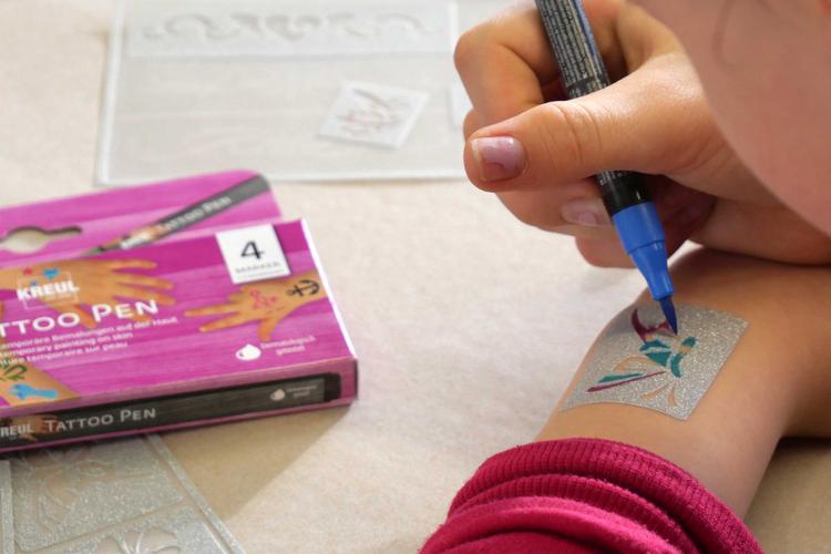 Fragen Antworten Anwendung KREUL Tattoo Pen Stift für Kinder Kind malt mit KREUL Tattoo Pen und Schablone ein Tattoo auf den Arm