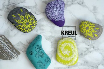 mit KREUL Acrylfarben verzierte, bunte Kieselsteine auf marmornem Untergrund 